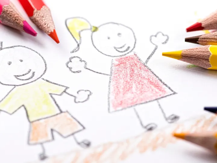 Lápices de colores sobre un dibujo infantil